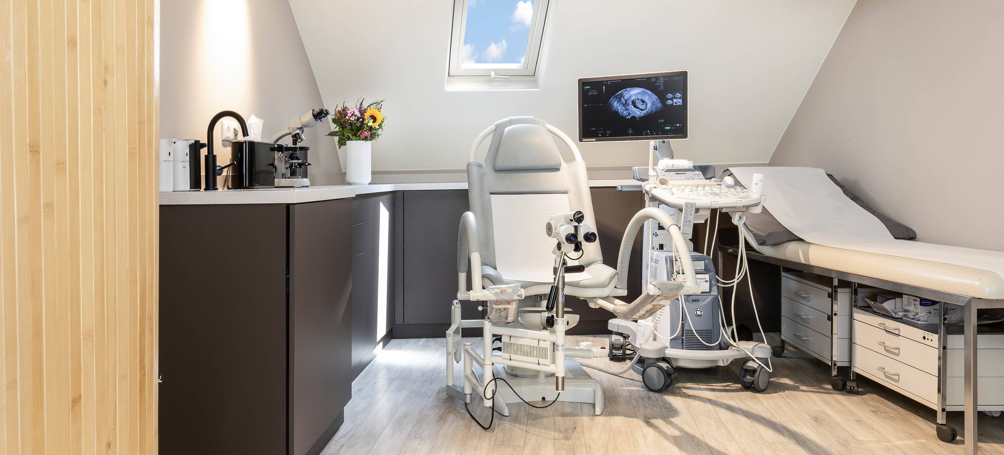 Modern eingerichtetes Behandlungszimmer mit Screen und gynäkologischem Stuhl in einer Frauenarztpraxis München Zentrum.