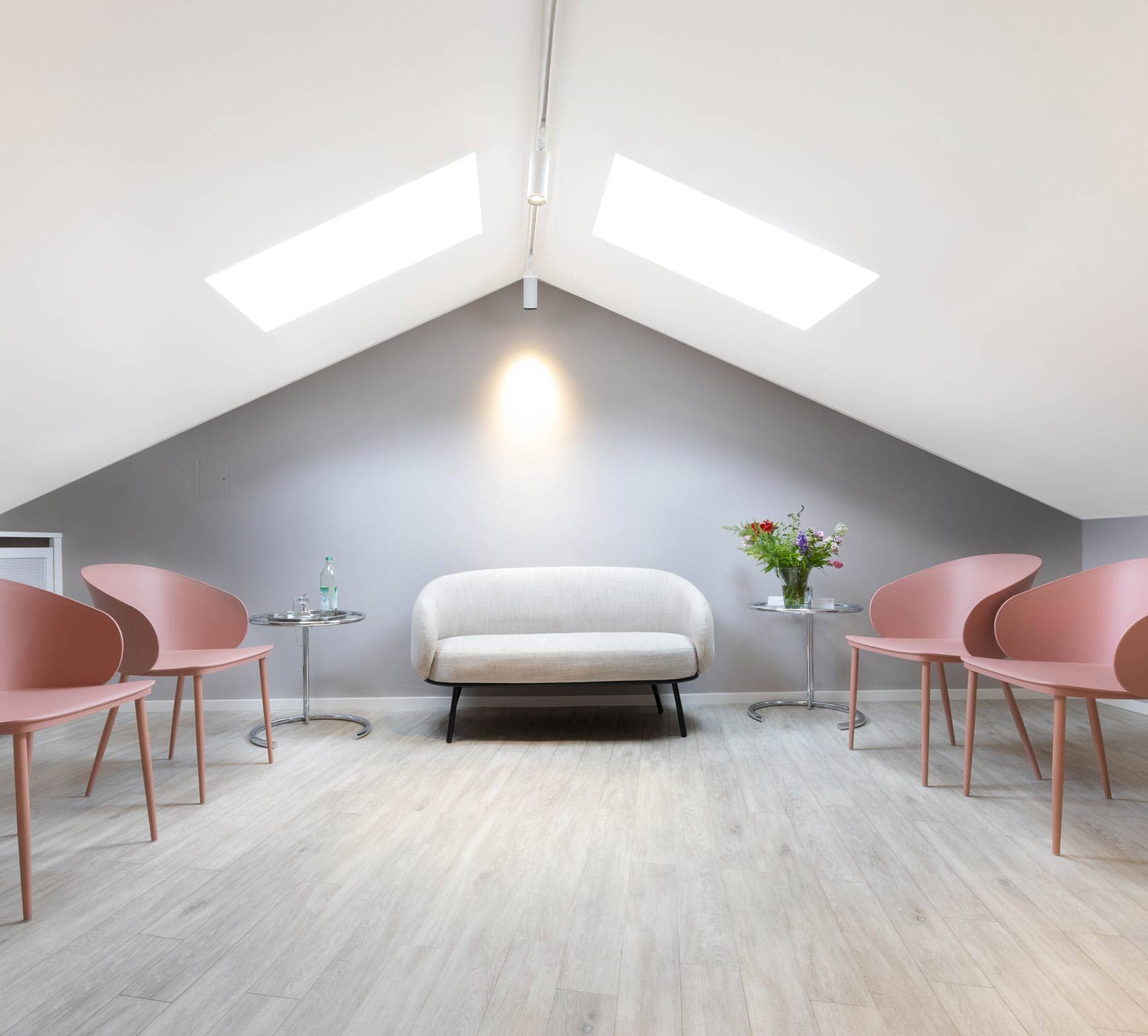 Kelles Wartezimmer mit rosa Stühlen und Blumenstrauß bei einer Frauenärztin in München Zentrum.